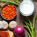Ein Nahaufnahme von fermentierten Lebensmitteln wie Kefir, Kimchi und Sauerkraut zusammen mit ballaststoffreichem Gemüse wie Spargel und Zwiebeln, symbolisiert Präbiotika und Darmgesundheit.